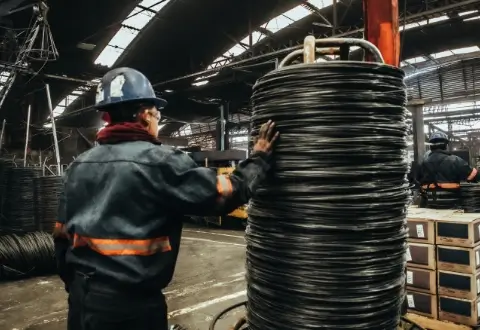 Trabajador de pie a un lado de rollo de alambre